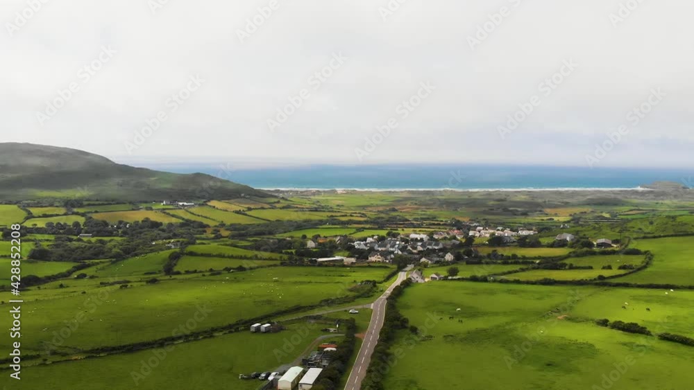 Slow Revealing Backwards Shot Of The Road Leading Into Llangennith Village, With Rhossili Beach and Rhossili Bay In The Background, In The Gower Peninsula, Llangennith, Wales Slow Revealing Backwards Shot Of The Road Leading Into Llangennith Village, With Rhossili Beach and Rhossili Bay In The Background, In The Gower Peninsula, Llangennith, Wales