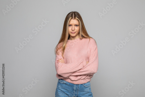 Confident woman with crossed hands on gray background.