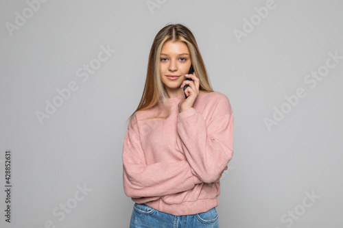 Smiling woman talking on the phone isolated on a grey background