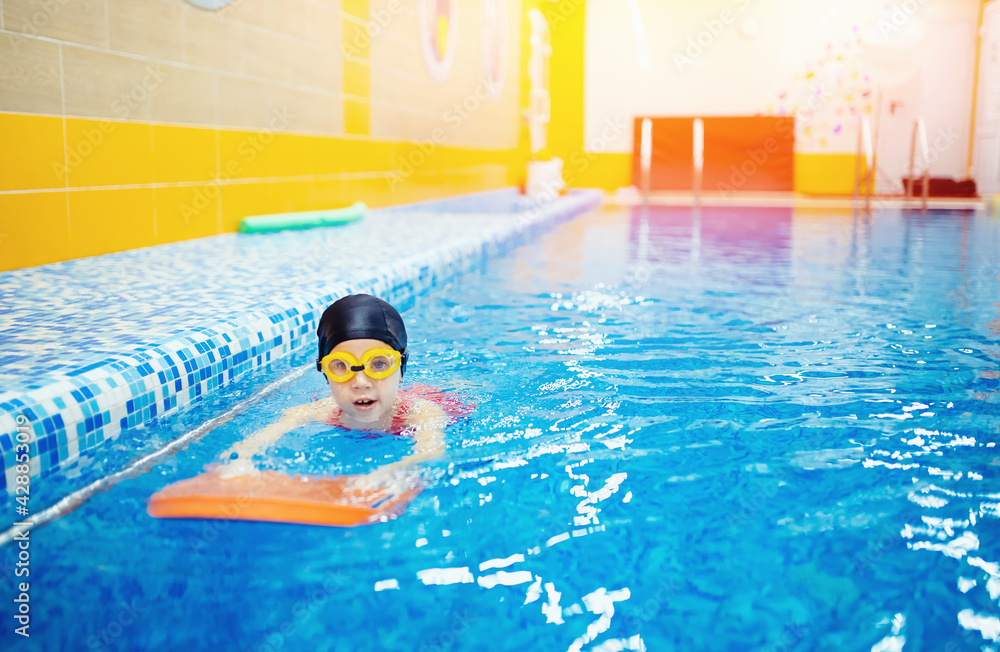 Concept training swimming child. Little kid girl with glasses learning to swim pool