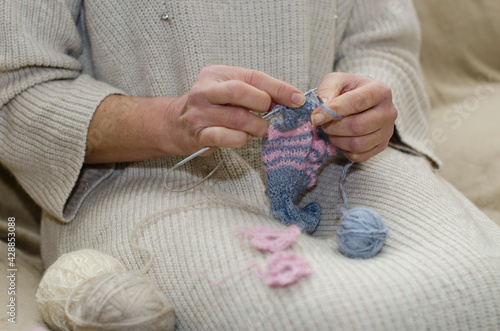 Hands of a woman who is engaged in knitting a scarf on knitting needles
