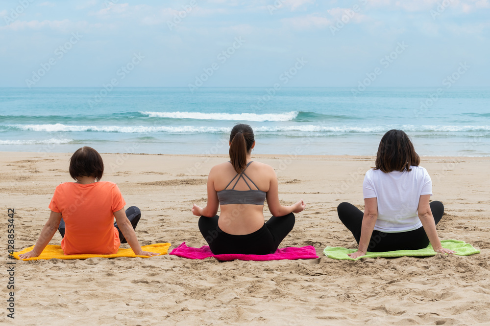 Three women relaxing and meditating at the beach