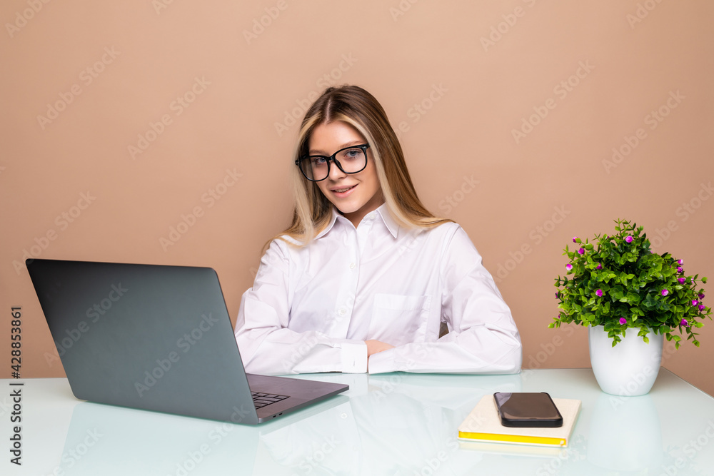 Portrait of beautiful young smiling business woman working on a laptop at office Portrait of beautiful young smiling business woman working on a laptop at office