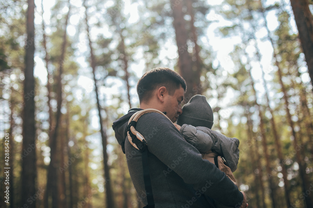 Father carrying his baby boy in ergo bag. Lifestyle, authentic moment. Concept of leisure outdoor Father carrying his baby boy in ergo bag. Lifestyle, authentic moment. Concept of leisure outdoor