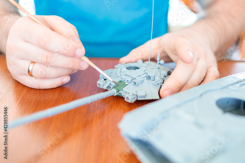 a man assembles a plastic tank model toy, tints the tank turret green