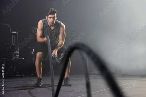 A Man Using Battle Ropes For Whipping Exercise in a Gym