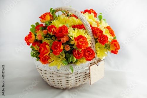 white basket with scarlet roses and yellow chrysanthemums. white background for cutting. card blank for the inscription copy space