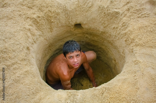 Homem num buraco na areia com seu rosto. photo