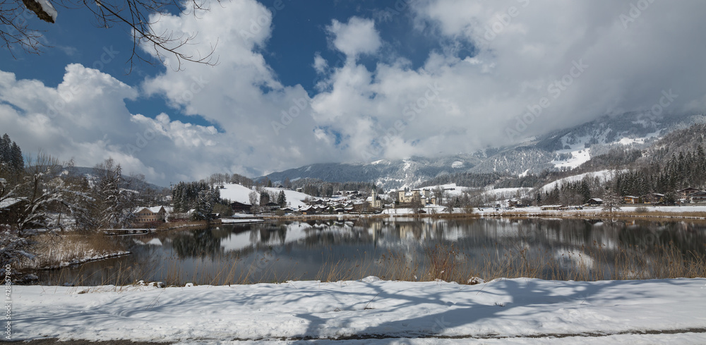 Panorama verschneiter Ort mit See.