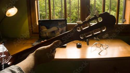 Man studying guitar on-line with a professor