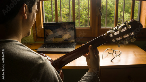 Man studying guitar on-line with a professor