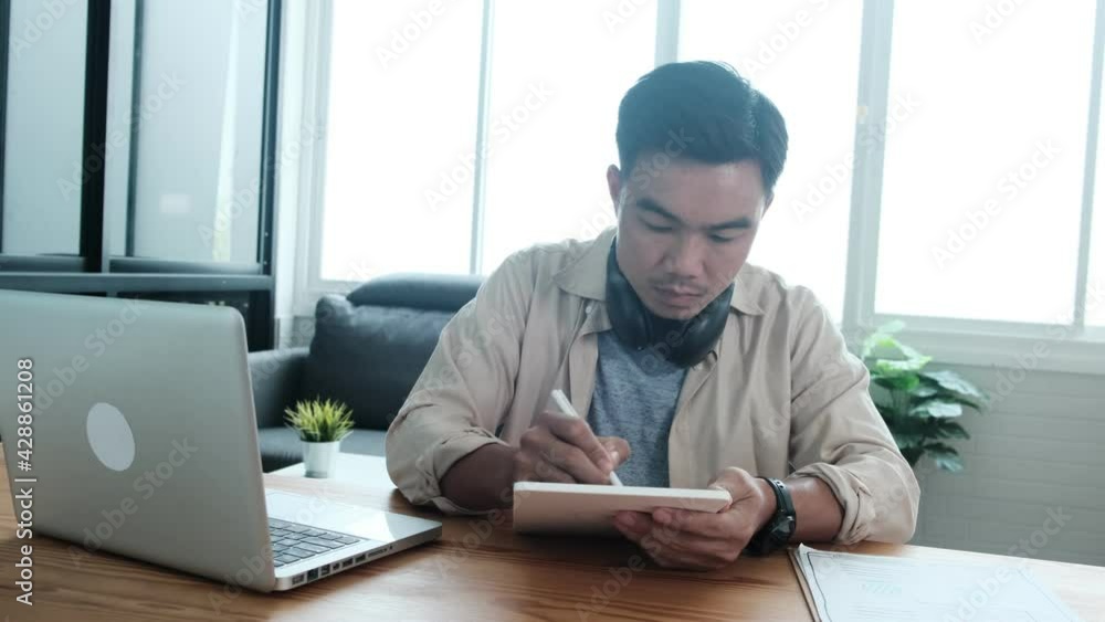 Web design asian man using graphics tablet pen sketching drawing drafting design work from paper into digital user interface UI UX, with laptop computer, professional working from modern home office Web design asian man using graphics tablet pen sketching drawing drafting design work from paper into digital user interface UI UX, with laptop computer, professional working from modern home office