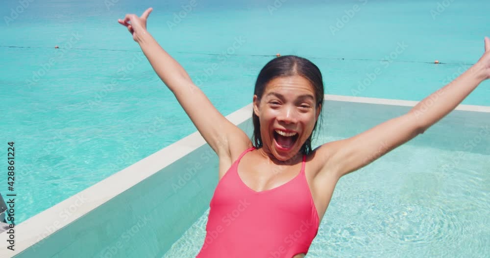 Vacation travel pool fun. Woman jumping in pool having fun laughing excited and happy enjoying luxury travel lifestyle. Girl screaming of joy with funny expression falling in swimming pool