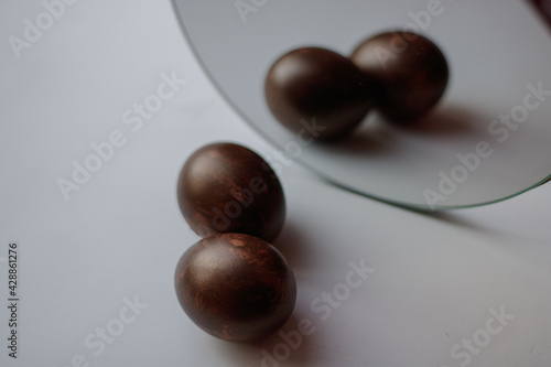 two painted eggs for easter in the reflection of the mirror on a white background