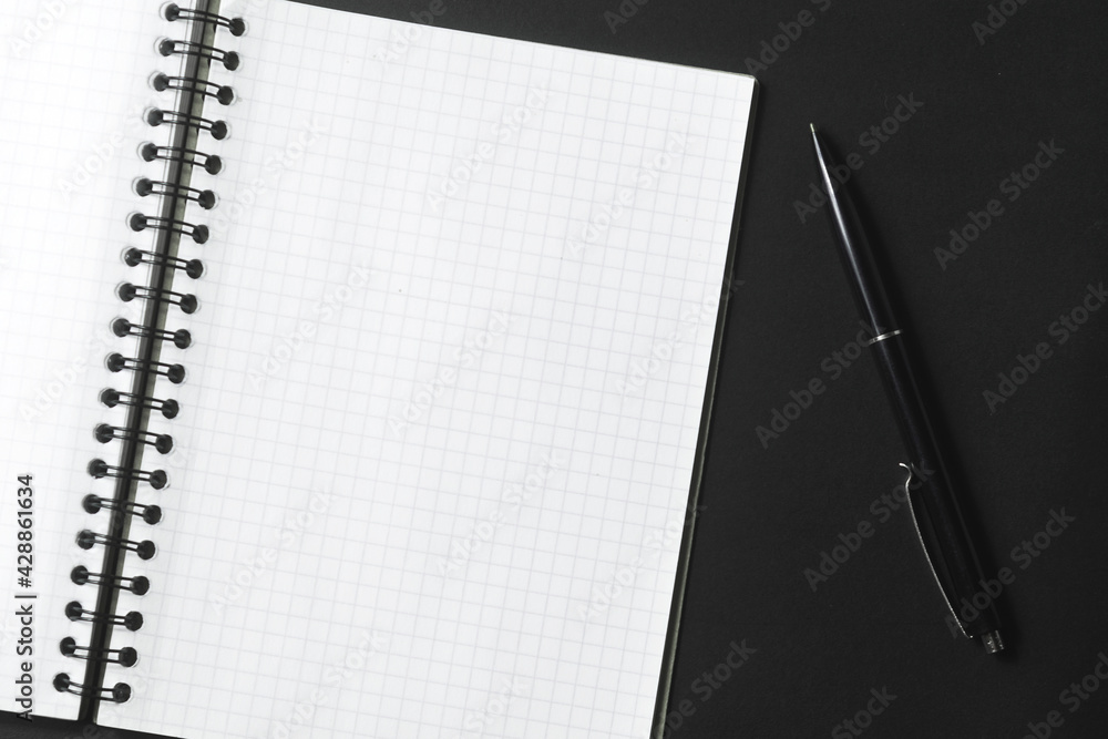 Раскрытый блокнот и черная ручка на темном фоне