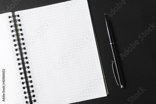 Раскрытый блокнот и черная ручка на темном фоне