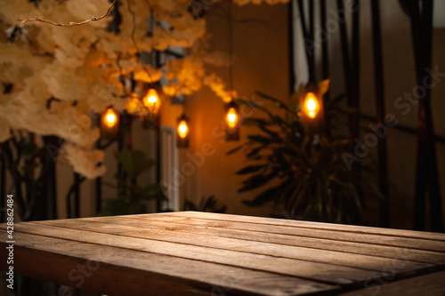 image of wooden table in front of abstract blurred background of restaurant lights