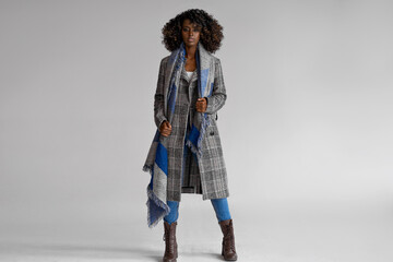 Female black model wear grey plaid coat with scarf with a trendy afro hairstyle isoalted on gray
