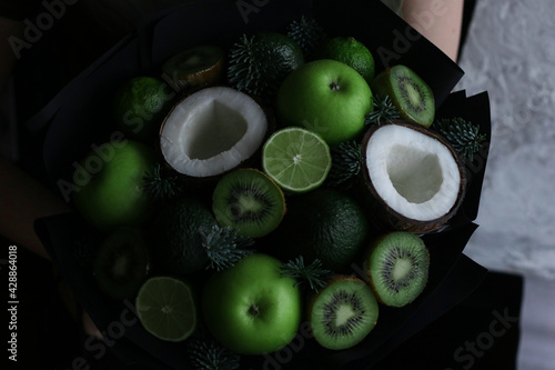 fruit bouquet as a gift from green fruits and coconut in black paper