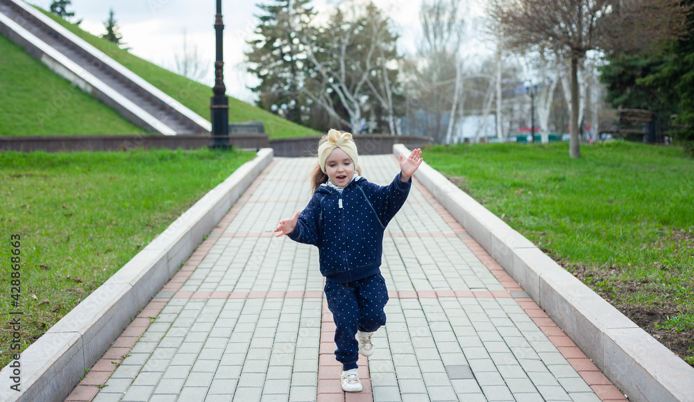 Little girl runs in the park. Active rest in the park. Cheerful child Little girl runs in the park. Active rest in the park. Cheerful child