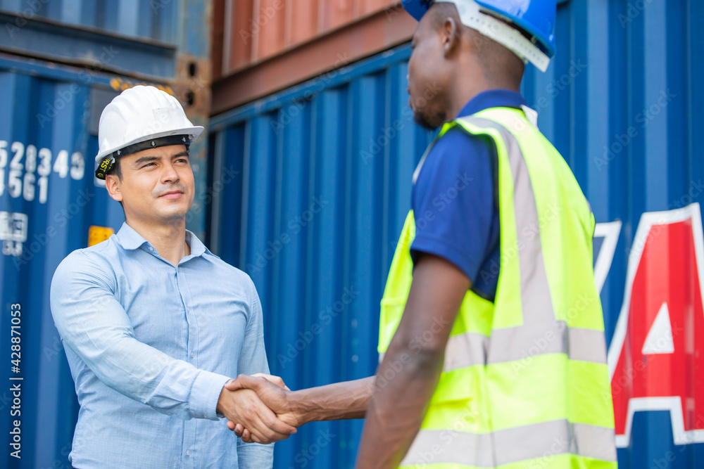 Engineer foreman handshaking with African American construction site worker. Man meeting, greeting or success work, People working for logistic export import business at container warehouse Engineer foreman handshaking with African American construction site worker. Man meeting, greeting or success work, People working for logistic export import business at container warehouse