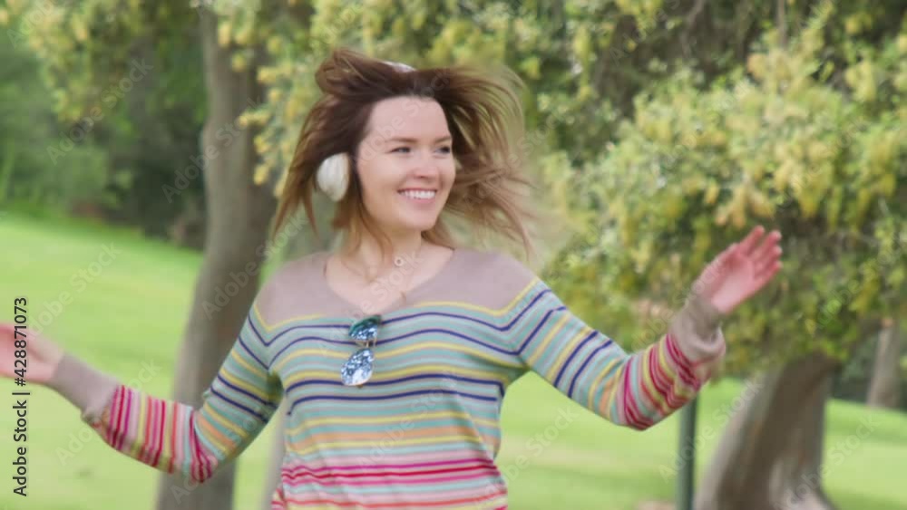 Slow motion happy young woman in wireless white headphones dancing and listening online music having fun in green summer park. Joy, people, happiness, lifestyle concept. RED Weapon Helium camera shot Slow motion happy young woman in wireless white headphones dancing and listening online music having fun in green summer park. Joy, people, happiness, lifestyle concept. RED Weapon Helium camera shot