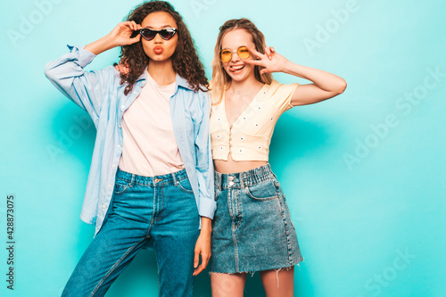 Konstfotografi Two young beautiful smiling international hipster female in trendy summer clothes