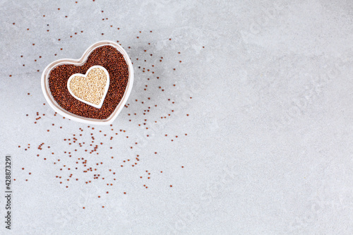 c Quinoa in heart-shaped bowl on stone background. photo