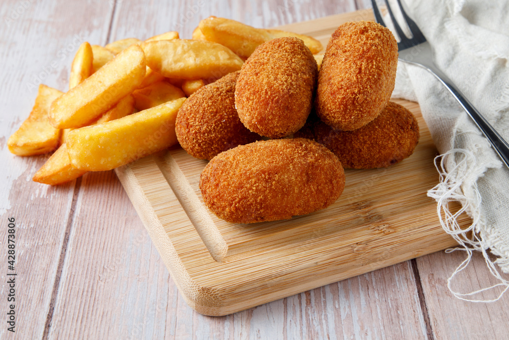 Naklejka premium Homemade croquettes with chips on wood cutting board