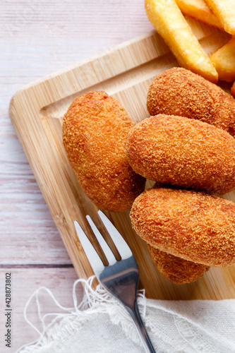 Homemade croquettes with chips on wood cutting board