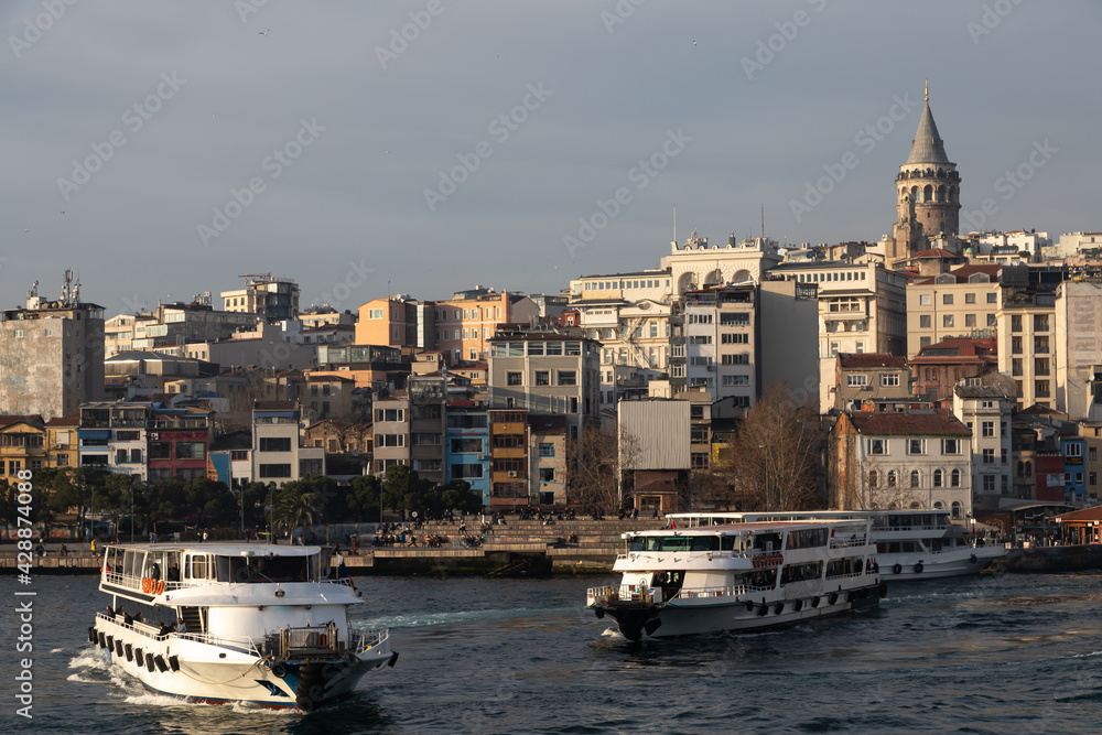 Urban landscape of the Istanbul embankment in the Golden Horn Bay. Sea transport departs from the pier. In the background, the Galata Tower and the buildings of the Karakoy district.