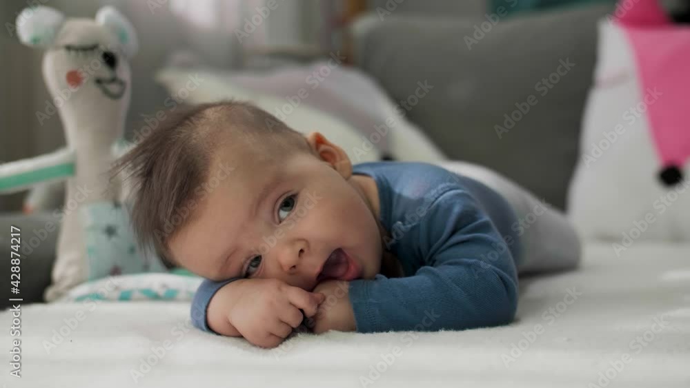 Cute little baby boy lying on stomach, learning to hold the head Cute little baby boy lying on stomach, learning to hold the head
