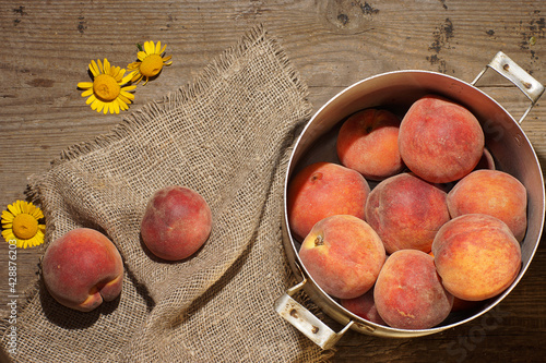 Two ripe peaches next to the pan are filled with them on the table