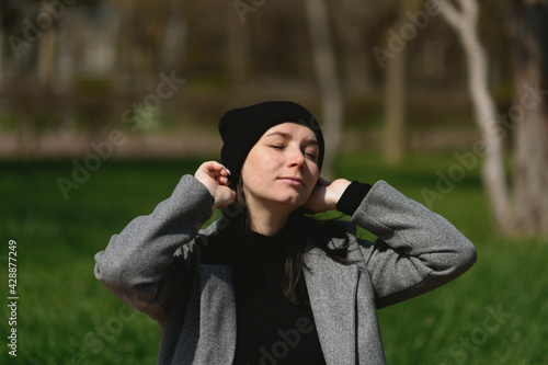 Beautiful girl sitting in the park and enjoying sunlight.