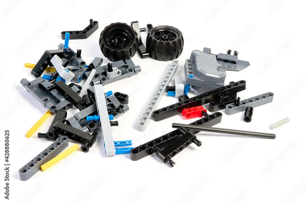 Plastic parts of the constructor, connecting elements and wheels for assembling movable models on a white background, floating focus. Plastic parts of the constructor, connecting elements and wheels for assembling movable models on a white background, floating focus.