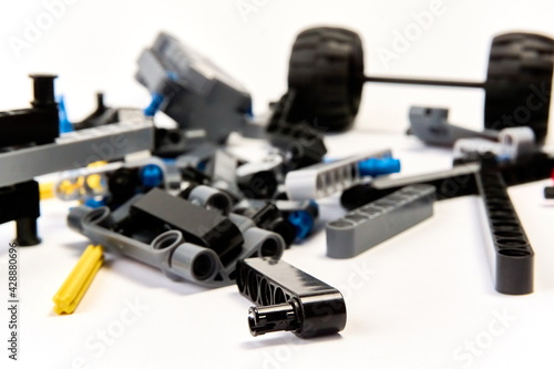 Plastic parts of the constructor, connecting elements and wheels for assembling movable models on a white background, floating focus.