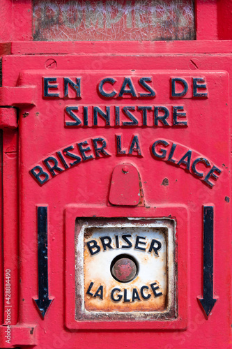 Wallpaper Mural Détail d'une ancienne borne d'appel d'urgence des pompiers en France, de couleur rouge, avec une phrase écrite en français : "en cas de sinistre, briser la glace" Torontodigital.ca