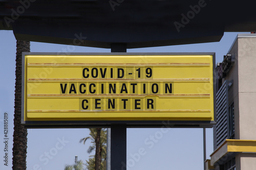 Billboard saying Covid-19 Vaccination Center. With palm trees and blue sky background. Coronavirus pandemic vaccine concept.