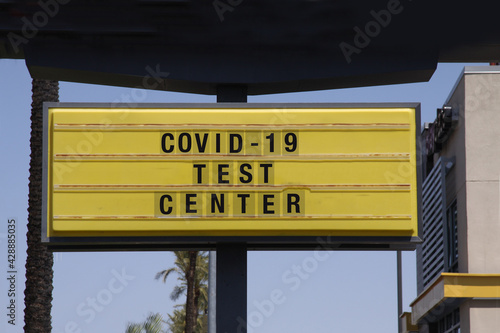 Billboard saying Covid-19 Test Center. With palm trees and blue sky background. Coronavirus pandemic vaccine concept.