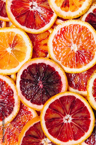 Bright colorful background of fresh ripe sliced blood oranges. Close up, flat lay, top view. Orange texture