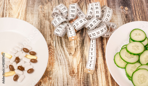 plate with cucumbers and pills on a wooden background. healthy food concept