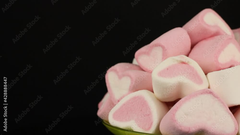 Marshmallows pink and white in the form of hearts rotate on black background. Marshmallows pink and white in the form of hearts rotate on black background.