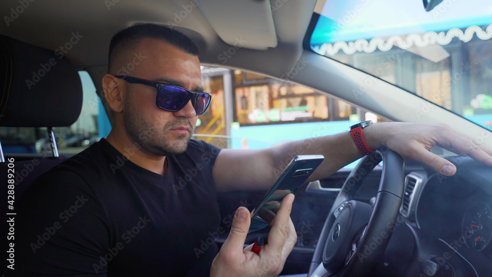 A man is building a route using a mobile phone while driving. The driver is talking on the phone while driving. A man is building a route using a mobile phone while driving. The driver is talking on the phone while driving.