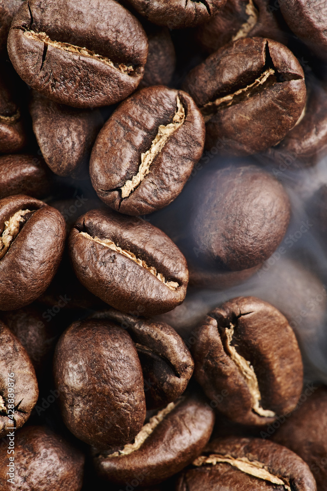 Close macro view of Viennese dark medium roasting process coffee beans with smoke with the second crack. Rich coffee taste and full body. Brown color Close macro view of Viennese dark medium roasting process coffee beans with smoke with the second crack. Rich coffee taste and full body. Brown color
