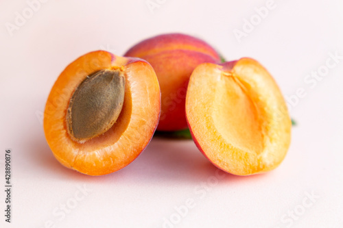 Ripe red homemade apricots with leaves on a pink background