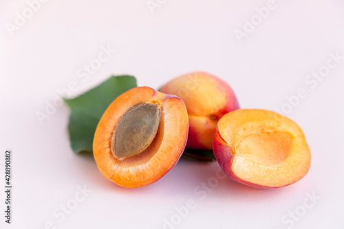 Ripe red homemade apricots with leaves on a pink background photo