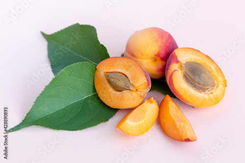 Ripe red homemade apricots with leaves on a pink background photo