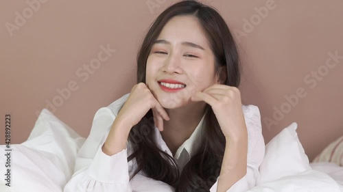Happy Asian woman smile and looking to camera on bed in the morning