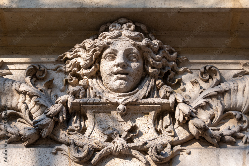 Visage de femme sculpté en pierre, probablement une allégorie de la fortune, ornement de façade d'un immeuble ancien de Paris, France Visage de femme sculpté en pierre, probablement une allégorie de la fortune, ornement de façade d'un immeuble ancien de Paris, France