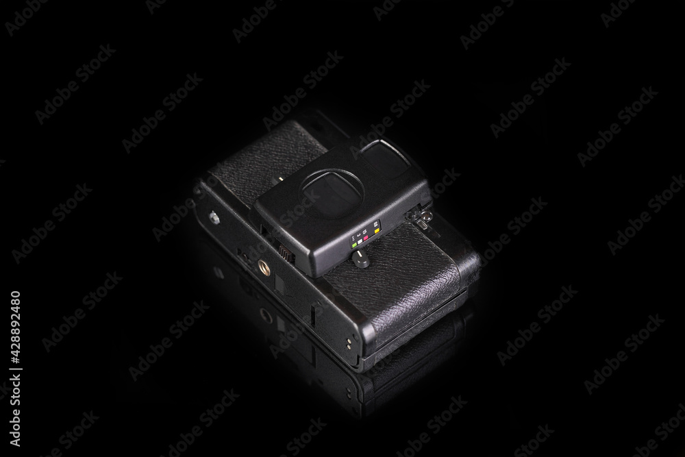 The old very popular automatic film camera on black glass background with reflection. The old very popular automatic film camera on black glass background with reflection.